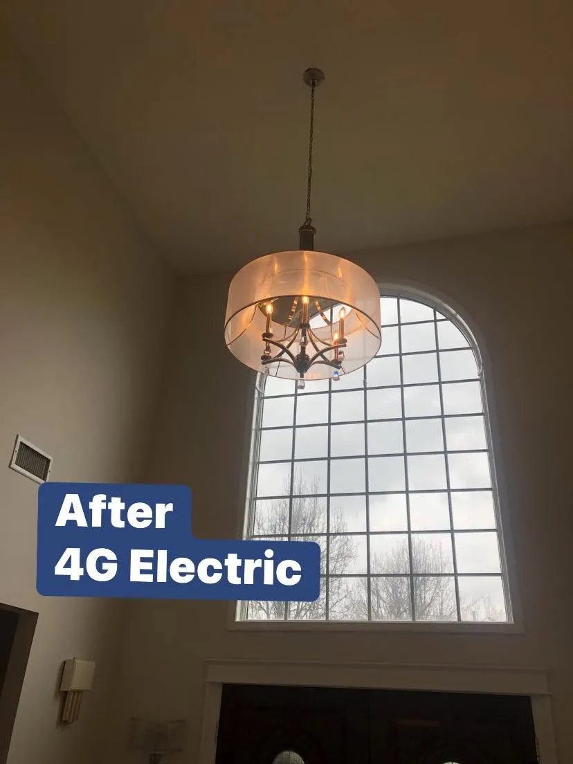 Drum-shade pendant chandelier hung beside a tall arched window